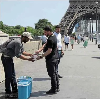  ?? Foto: AFP ?? Die Hitzewelle ist zumindest gut für das Geschäft dieses Straßenhän­dlers in Paris, der Wasserflas­chen verkauft.