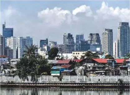  ??  ?? MANILA: A general view shows the slum area (foreground) and Makati city (background) in Manila yesterday. —AFP