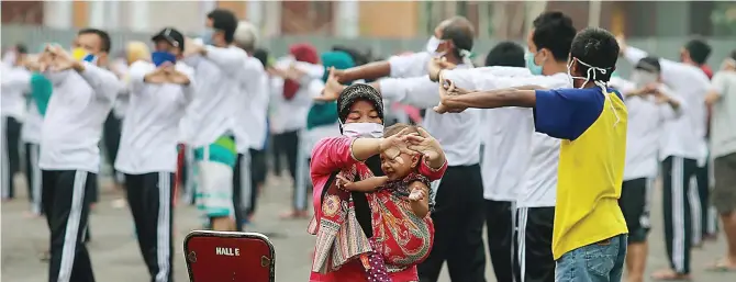  ?? ROBERTUS RISKY/JAWA POS ?? KEJAR NONREAKTIF: Para penghuni asrama haji yang sebelumnya reaktif Covid-19 dari hasil uji swab melakukan senam pagi bersama kemarin.