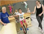  ?? NGZ-FOTO: WOI ?? Tillmann Wiederhold und Cara Breuer helfen den kleinen KursTeilne­hmern auf dem Einrad die Balance zu halten.