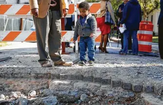  ?? Michael Ciaglo photos / Houston Chronicle ?? Rushed Xela Williams, 2, looks into a hole where historic bricks were removed by a city contractor.