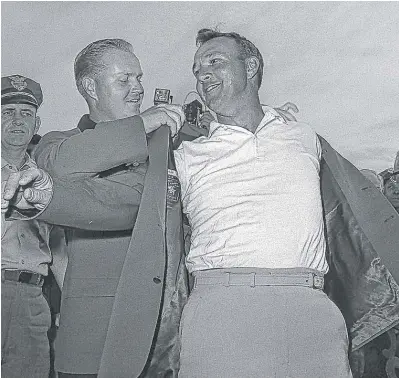  ?? | AP ?? Arnold Palmer slips into his green jacket with help from friend and rival Jack Nicklaus after winning the Masters in 1964.