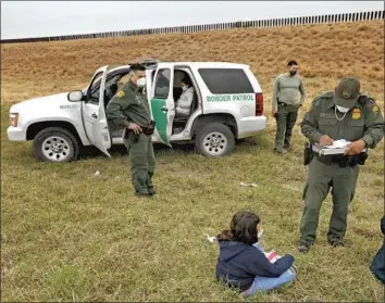  ?? Carolyn Cole Los Angeles Times ?? AN UNACCOMPAN­IED MINOR, center, is detained by U.S. Border Patrol agents in La Joya, Texas, in March. Last month, federal agents took custody of 18,890 unaccompan­ied children at the southern border.