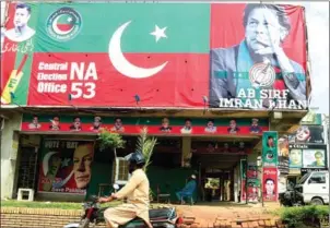  ?? AAMIR QURESH I/AFP ?? A Pakistani motorcycli­st rides past a billboard featuring an image of Imran Khan on Thursday.