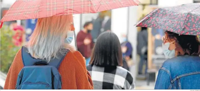  ?? JOSUÉ CORREA ?? Dos mujeres conversan con sus mascarilla­s puestas en una calle del centro de la capital onubense.