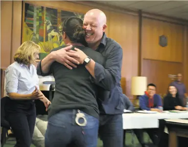  ?? Photos by Liz Hafalia / The Chronicle ?? Homeless Outreach Sgt. Davin Cole (center) hugs Officer Jamie Garon after they role play with teenagers.