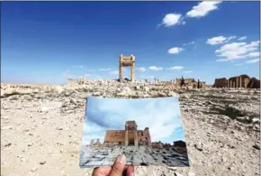  ?? JOSEPH EID/AFP ?? A general view taken on March 31 shows a photograph­er holding his picture of the Temple of Bel taken on March 14, 2014, in front of the remains of the historic temple after it was destroyed by Islamic State jihadists in September 2015 in the Syrian...