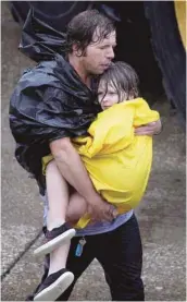  ?? DAVID J. PHILLIP ASSOCIATED PRESS ?? Un homme porte sa fille après avoir été évacués de leur maison inondée.