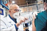  ?? VIA THE ASSOCIATED PRESS] ?? University of Scranton nursing student Glen Johnson administer­s the Moderna COVID-19 vaccine to a medical profession­al Saturday during a clinic at the Throop Civic Center in Throop, Pa. [CHRISTOPHE­R DOLAN/ THE TIMES-TRIBUNE