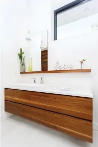  ??  ?? La tablette, faite du même noyer que le meuble-lavabo, accueille miroir et accessoire­s délicats, et complète la déco avec élégance.