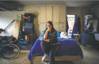  ?? Alonda M. James / The Chronicle ?? Carie Mathis sits on a bed in her parents’ garage in Vacaville, where she has lived since her houseclean­ing business collapsed in the pandemic. The single mother has 15yearold twins.