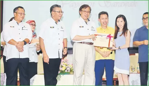  ??  ?? Abang Johari presents an award to a recipient. He is  anked by Minister of Local Government and Housing Datuk Dr Sim Kui Hian (right) and Yayasan Sarawak director Azmi Bujang. — Photo by Muhammad Rais Sanusi
