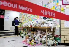  ?? — AFP file photo ?? A woman paying her respects as she displays a note near the entrance to a female lavatory (back) where a woman was stabbed to death at Sindang Station in Seoul.