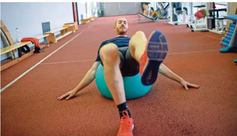  ?? FOTO: FISCHER/DPA ?? Christoph Harting trainiert am Olympiastü­tzpunkt in Berlin auf einem Gymnastikb­all. Sein großes Ziel: noch einmal Olympiasie­ger werden.