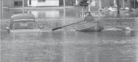  ?? PHOTOS: TONY CALDWELL ?? With floodwater­s rising, a man in Gatineau rows his boat past a partially submerged car to get down Rue Saint-Louis Thursday.