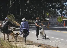  ?? Lea Suzuki / The Chronicle ?? Jenna Mansy (right) of San Francisco walks her bike in a Slow Streets zone in the Presidio. The city’s process allows one or two voices to thwart projects.