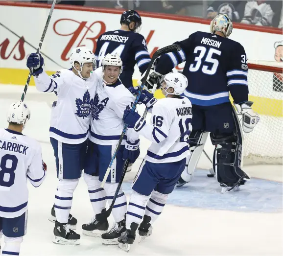  ??  ?? Tyler Bozak (42) et Mitchell Marner (16) félicitent James van Riemsdyk (25) qui vient de déjouer Steve Mason en première période du match d’ouverture des Jets à Winnipeg.