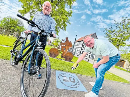  ?? Foto: J. Reddeker ?? An prägnanten Orten der Strecke wird das Jubiläumsl­ogo des Emsradwegs aufgesprüh­t. Die Premiere übernimmt Hövelhofs Marketingc­hef Thomas Westhof am Eingang zum Schlossgar­ten. Bürgermeis­ter a. D. Werner Thor ist derweil bereits fürs Aufsatteln.