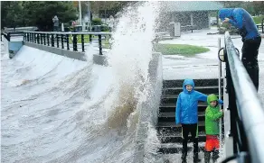  ?? — AP FILES ?? Maxwell Gendreau, 12, left, brother Cameron, 11, and father Eric all brace for a soaking from the spray as the storm moves in at Silverdale Waterfront Park in Silverdale, Wash., on Saturday.