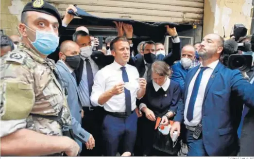  ?? THIBAULT CAMUS / EFE ?? El presidente francés, Emmanuel Macron, se quita la máscara mientras visitaba ayer una calle devastada de Beirut.