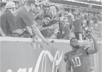  ?? Elizabeth Conley / Houston Chronicle ?? UH defensive tackle Ed Oliver, right, takes a selfie with fans after the Cougars’ 38-3 rout of Rice at TDECU Stadium on Saturday night. Oliver had six tackles and a forced fumble in the game.