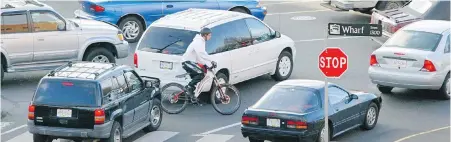  ?? DARREN STONE, TIMES COLONIST ?? A cyclist weaves through traffic on Wharf Street during rush hour. Unlicensed people using public roads should be subject to the same legal requiremen­ts as licensed drivers, Steve Wallace writes.