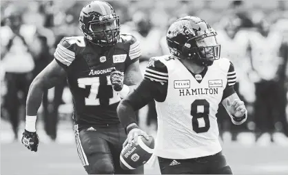  ?? COLE BURSTON
THE CANADIAN PRESS ?? Argonauts defensive end Rakim Cox, left, chases down Hamilton Tiger-Cats quarterbac­k Jeremiah Masoli during second-half CFL action in Toronto on Saturday. Masoli threw four touchdown passes as the Ticats prevailed in the contest, 36-25.