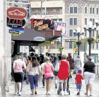  ?? William Luther / Staff photograph­er ?? People pass the popular tourist attraction­s targeted for ouster across Alamo Plaza from the Shrine of Texas Liberty.