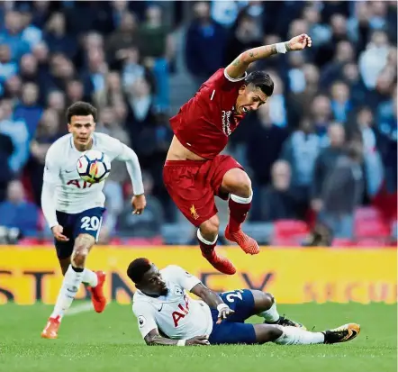  ?? — Reuters ?? Close call: Liverpool’s Roberto Firmino jumping to avoid a tackle by Tottenham’s Serge Aurier in their match at Wembley on Sunday.