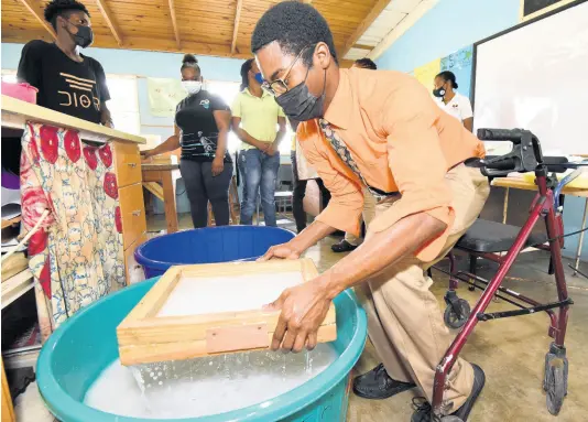  ??  ?? Jamar Patterson collects dissolved recycled paper in a mould during a training programme for unattached deaf youths.