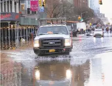  ?? RICHARD DREW/AP ?? A truck fords a flooded street in front of the Lincoln Center for the Performing Arts on Monday in New York. A water main break flooded streets on Manhattan’s Upper West Side near the Lincoln Center and snarled subway service during the morning commute.