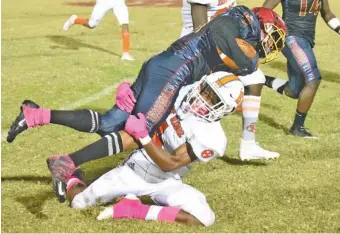  ?? STAFF PHOTO BY MATT HAMILTON ?? East Ridge’s Desmon Drake, on ground, wraps up Howard’s Deorean Elder during Friday night’s game at Howard. Drake had a 65-yard kickoff return for a touchdown to open the second half as the Hustlin’ Tigers won the Region 2-4A matchup 14-10.