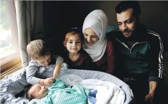  ?? PHOTOS: LEAH HENNEL ?? Afraa Bilan, 22, and her husband Muhammad Bilan, 29, with their three children, Nael, 3, left, Naya, 5 and Justin Trudeau Adam, born May 4, at their home in Calgary.