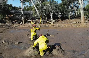  ?? MARCIO JOSE SANCHEZ/AP PHOTO ?? A Cal Fire search and rescue crew walks through mud near homes damaged by storms in Montecito, Calif., on Friday. The mudslide, touched off by heavy rain, took many homeowners by surprise early Tuesday, despite warnings issued days in advance that...