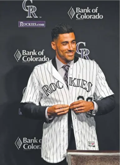  ?? John Leyba, The Denver Post ?? New Rockies first baseman Ian Desmond flashes a smile while putting on his jersey at a news conference at Coors Field in Denver on Tuesday. Rockies General manager Jeff Bridich introduced him.