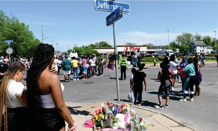  ?? Photograph: Usman Khan/AFP/Getty Images ?? Mourners gather near a Tops Grocery store in Buffalo, New York, on Sunday, after a white gunman killed 10 people in a racially motivated rampage Saturday.