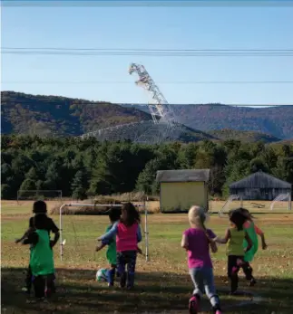  ??  ?? Kids play behind the Green Bank Elementary­Middle School as the Robert C Byrd Green Bank Telescope looms in the background.