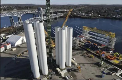  ?? (AP/Ted Shaffrey) ?? While wind farm towers (left) stand on the ground, a generator and its blades (right) are readied for transport to the South Fork Wind farm site at State Pier in New London, Conn., earlier this month.