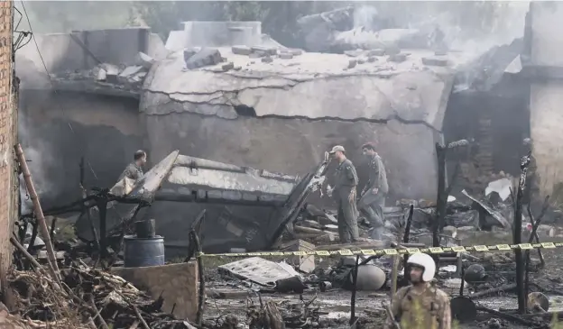  ?? PICTURE: AFP/GETTY IMAGES ?? 0 Rescuers search the site near Rawalpindi for clues as to why the military aircraft caught fire and crashed into homes, killing and injuring many