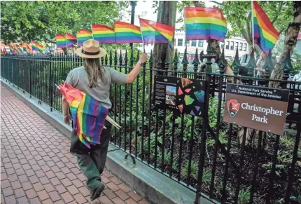  ??  ?? A National Park Service ranger places rainbow flags around Christophe­r Park in New York in June 2019.