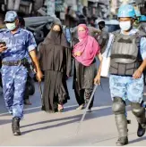  ?? Reuters ?? Veiled Muslim women walk near members of Rapid Action Force patrolling a neighborho­od during a lockdown in the area in Ahmedabad on Monday.