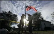  ?? ERIC GAY - THE ASSOCIATED PRESS ?? A law enforcemen­t officer helps a man change a flag to half-staff near the scene of a shooting at the First Baptist Church of Sutherland Springs to honor victims, Monday, in Sutherland Springs, Texas. A man opened fire inside the church in the small...