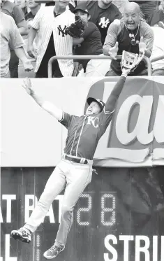  ?? Frank Franklin/Associated Press ?? ■ Kansas City Royals right fielder Brett Phillips leaps to catch a ball hit by New York Yankees’ Austin Romine for an out as a fan reaches for the ball during the fourth inning of a baseball game Sunday in New York.