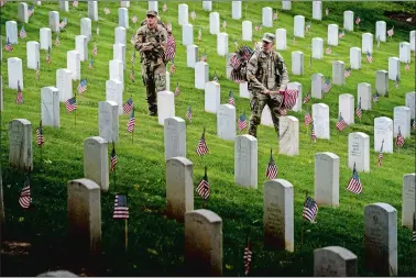  ?? ANDREW HARNIK/AP PHOTO ?? Members of the 3rd U.S. Infantry Regiment, also known as The Old Guard, place flags in front of each headstone for “Flags-In” at Arlington National Cemetery in Arlington on Thursday to honor the nation’s fallen military heroes ahead of Memorial Day.