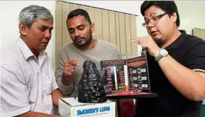  ??  ?? Closer look: (From left) Oo Eng Hock, 54, Sulaiman and Luqman looking at a sample lung of a smoker.