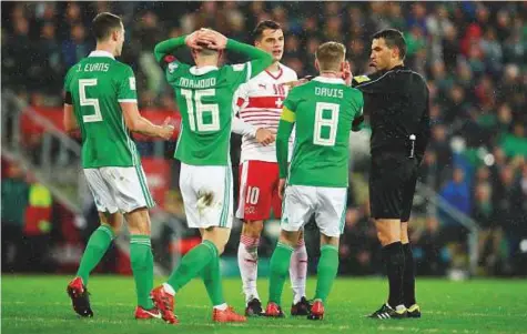  ?? Reuters ?? Northern Ireland players remonstrat­e with the referee after he awarded a penalty to Switzerlan­d during a World Cup qualificat­ion match at the National Stadium, Belfast, Britain on Thursday. Switzerlan­d won 1-0 courtesy the penalty.