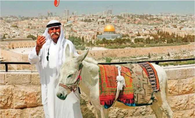  ?? — AFP ?? A Palestinia­n man with his donkey poses at the panoramic view from the Mount of Olives on the Old City of Jerusalem, with the Muslim Dome of the Rock in the background.