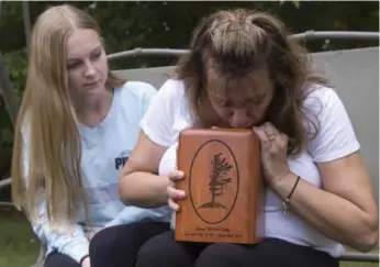  ?? FRANK GUNN/THE CANADIAN PRESS ?? Denise Lane, with daughter Megan, kisses the urn containing the ashes of her son, Shawn, at their Innisfil home.