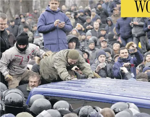  ?? PHOTOS: SERGEI CHUZAVKOV/AFP/GETTY IMAGES ?? Supporters of former Georgian president Mikheil Saakashvil­i attempt to release him from a police van after he was arrested in Kyiv, Ukraine, on Tuesday. The politician also served as governor of Ukraine’s Odessa region.