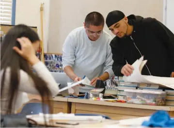  ?? (Francine Orr/Los Angeles Times/TNS) ?? TEACHER JOEL WING and Desmond Pueyrredon, 17, right, go over paperwork in Wing’s Oakland classroom.